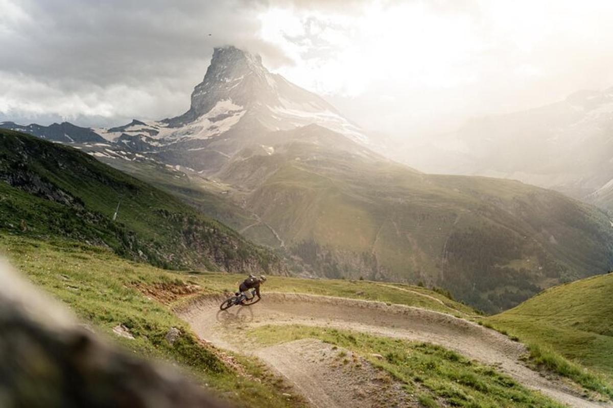 a person riding a bike on a dirt road in front of a mountain