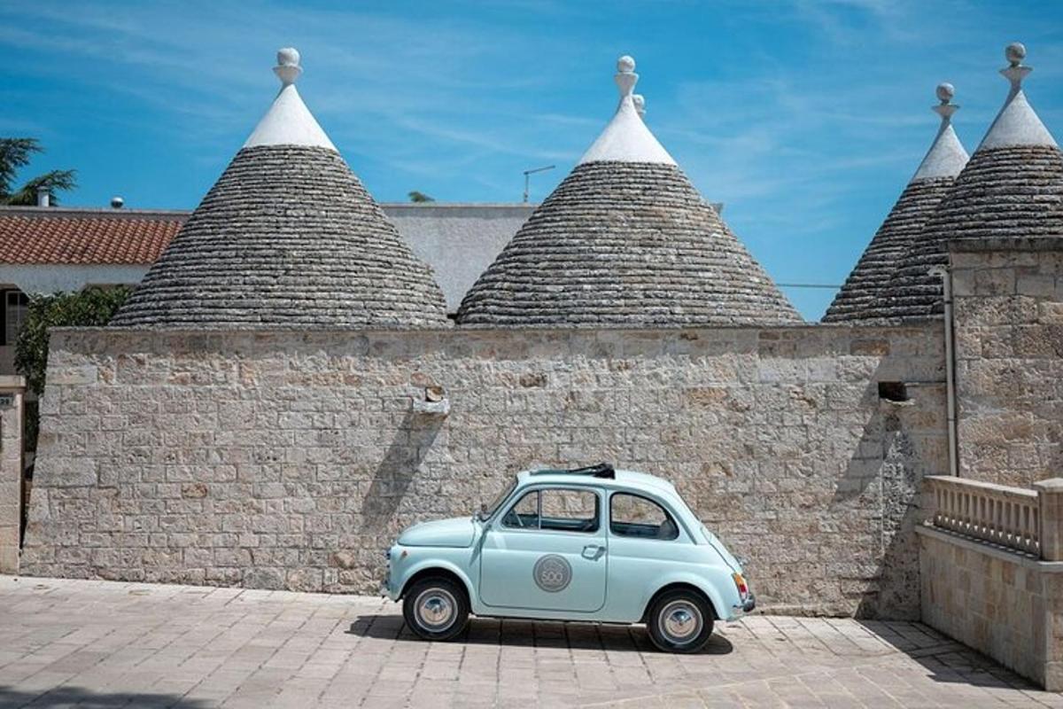 um pequeno carro azul estacionado em frente a um muro de tijolos