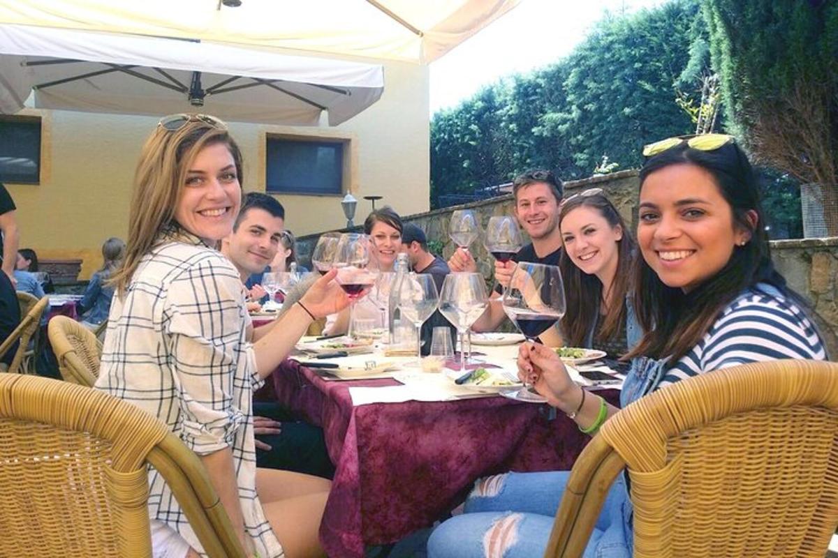 un grup de persones assegudes a una taula amb copes de vi