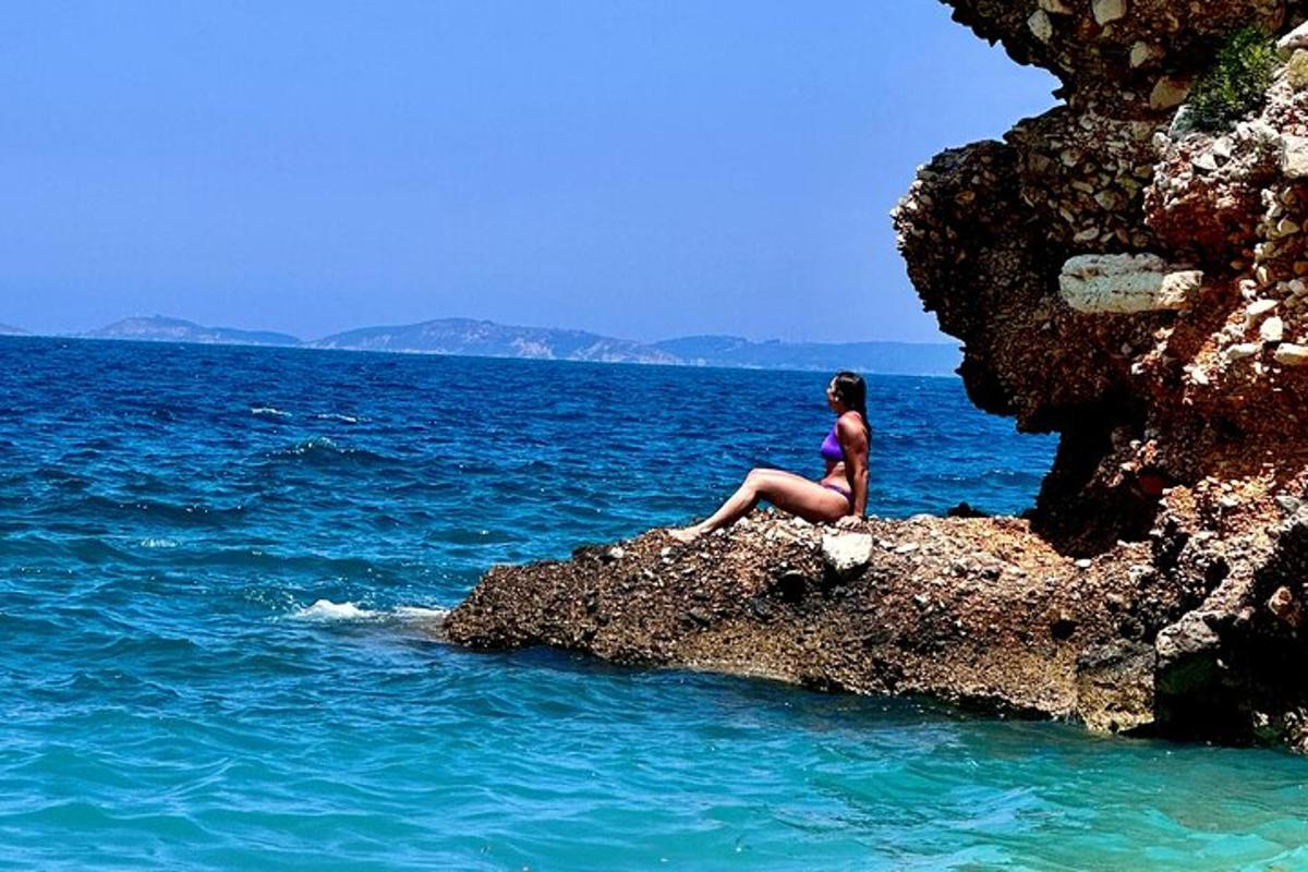 a woman sitting on a rock in the ocean