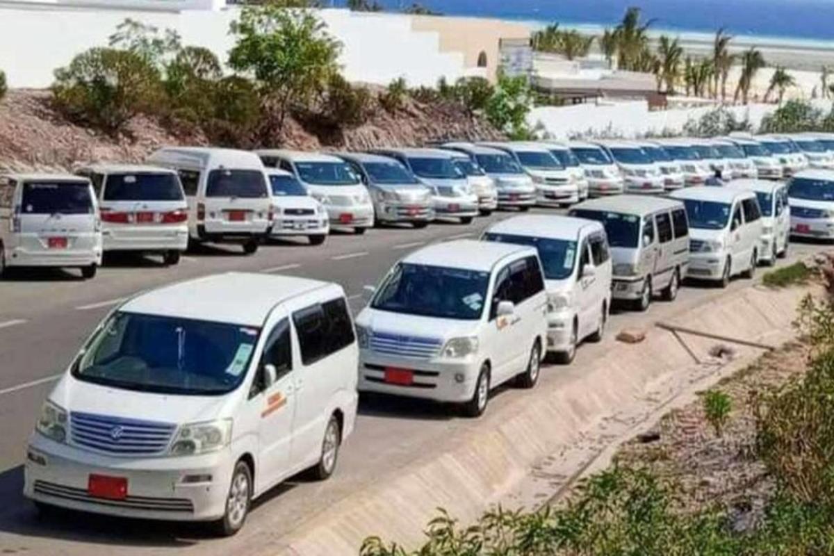 a line of white vans parked in a parking lot