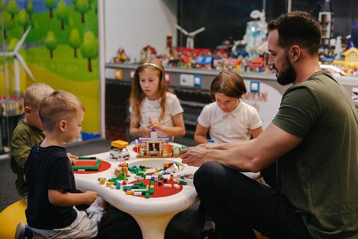 grupp lapsi istub laua ümber ja neil on lego tort käes.