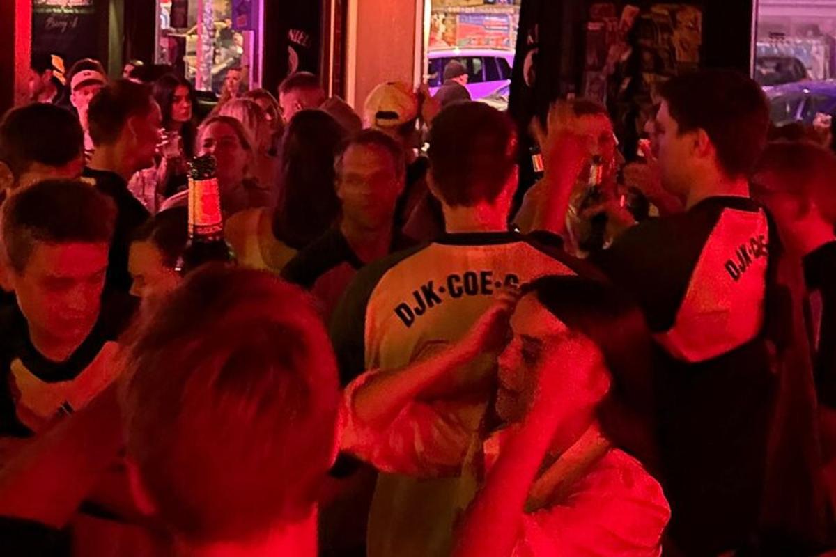 μια ομάδα ανθρώπων που στέκονται σε ένα πλήθος σε ένα μπαρ