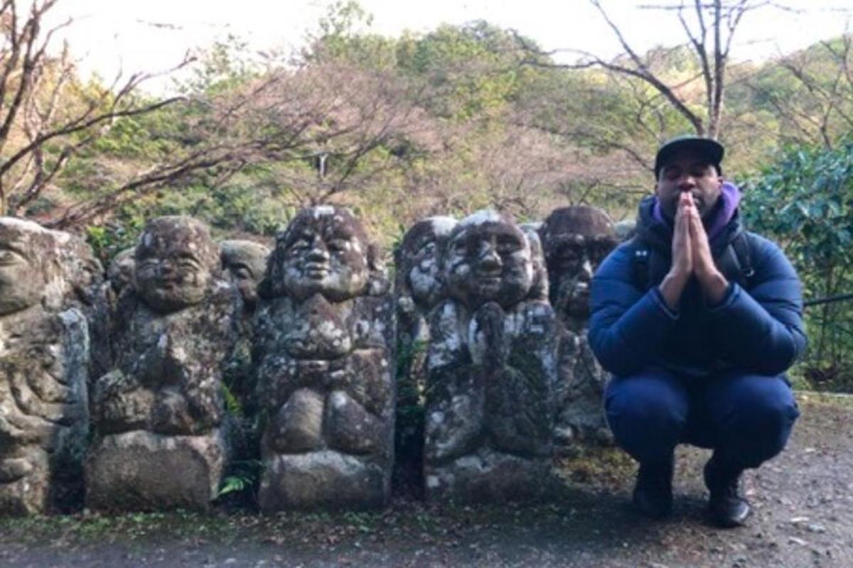 Un hombre arrodillado frente a una estatua de cabeza de piedra
