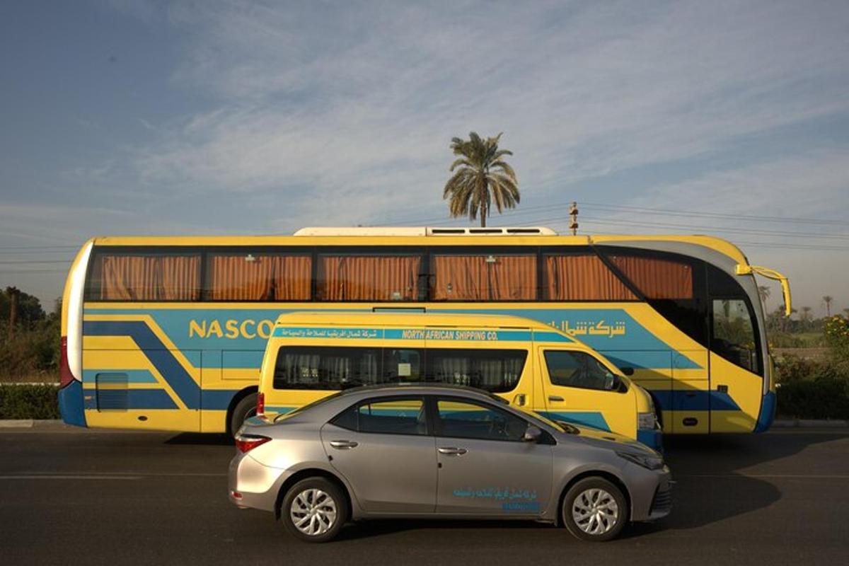 sebuah bas kuning dan biru dan sebuah kereta di tempat letak kereta
