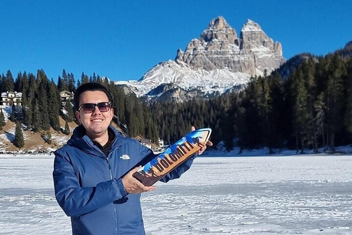 un uomo che tiene uno snowboard davanti a una montagna