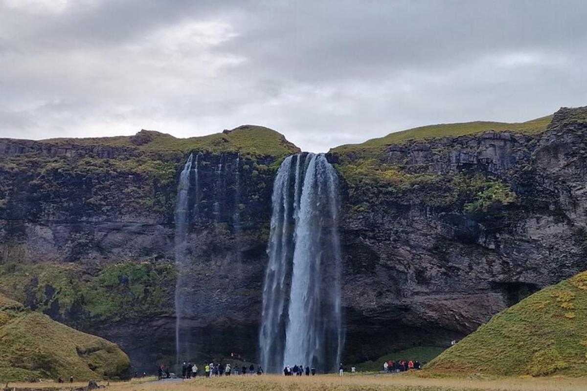 um grupo de pessoas em pé em frente a uma cachoeira