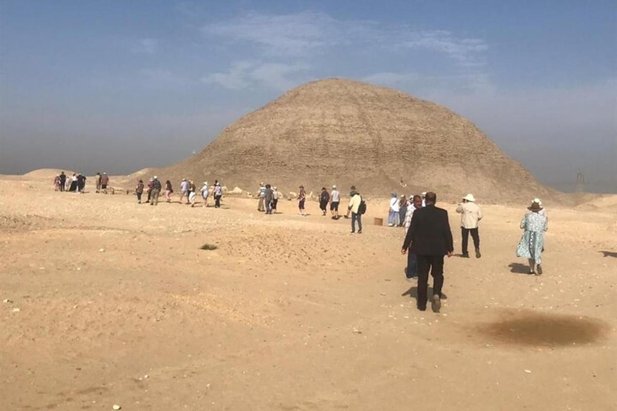 skupina ľudí kráčajúcich pred pyramídou