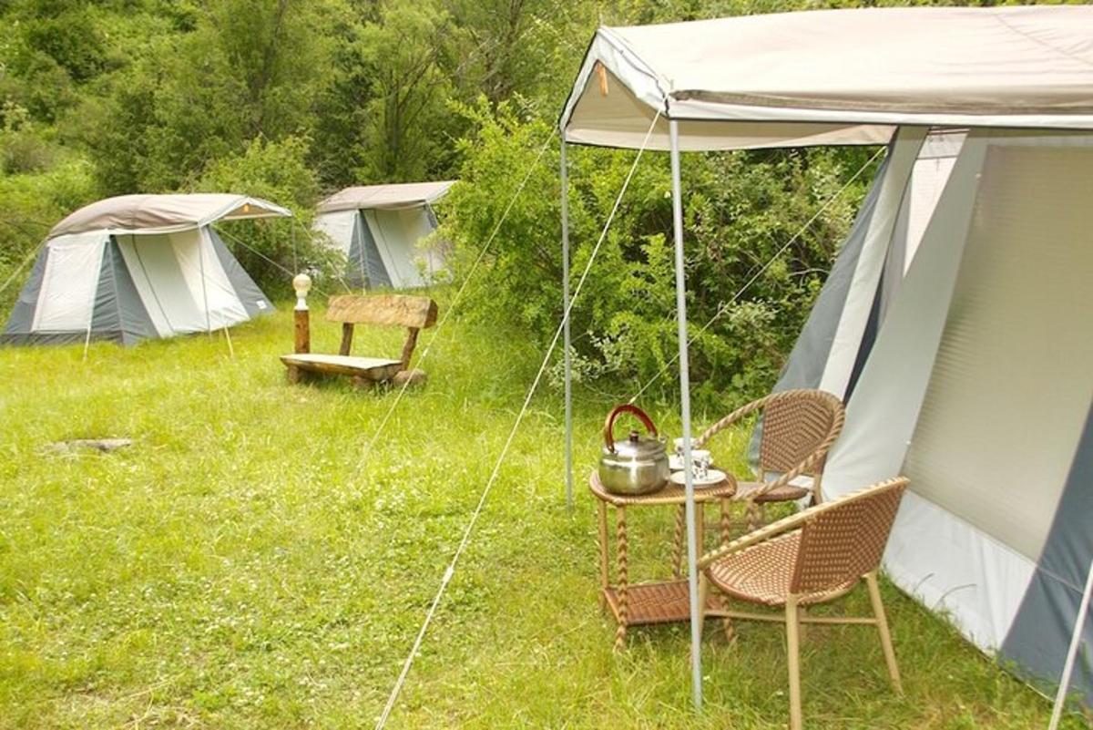 a group of tents in a field with a table and chairs