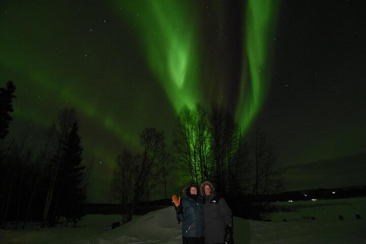 Tveir menn standa í snjónum undir norðurljósum