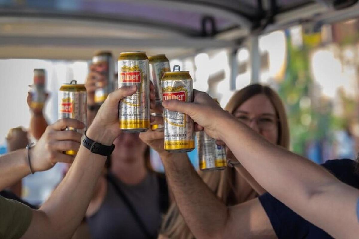 a group of people holding up four bottles of beer