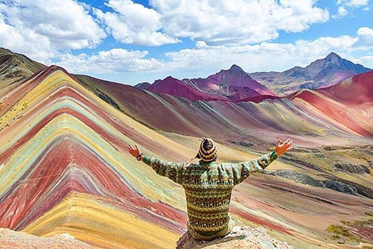 un home assegut en una roca mirant una pintura de muntanyes