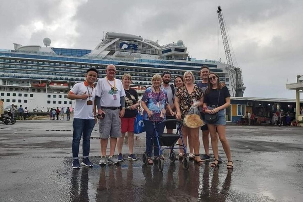 um grupo de pessoas em pé em frente a um navio de cruzeiro