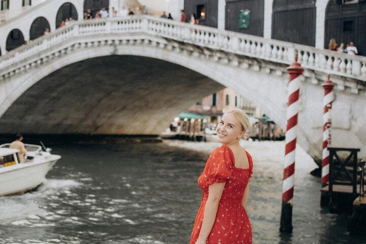 una dona amb un vestit vermell dempeus davant d'un pont