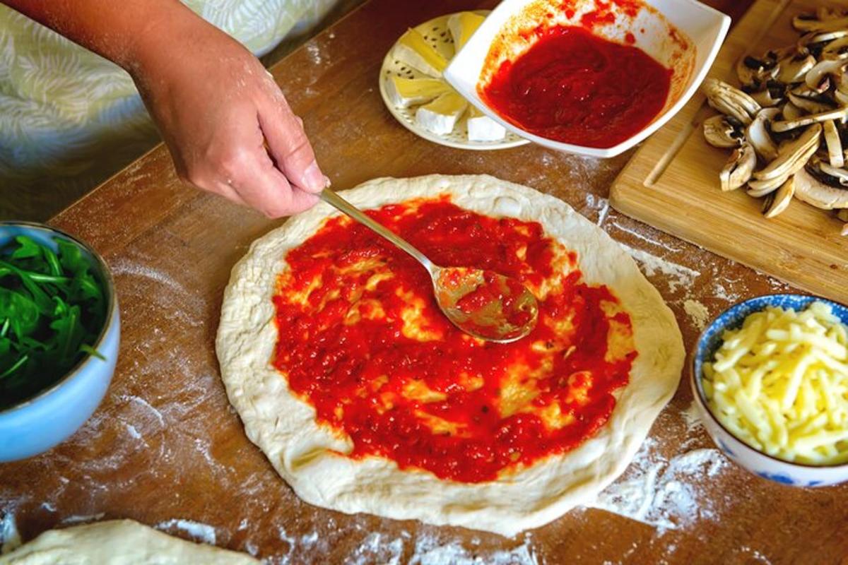 una persona haciendo una pizza con una cuchara sobre una mesa