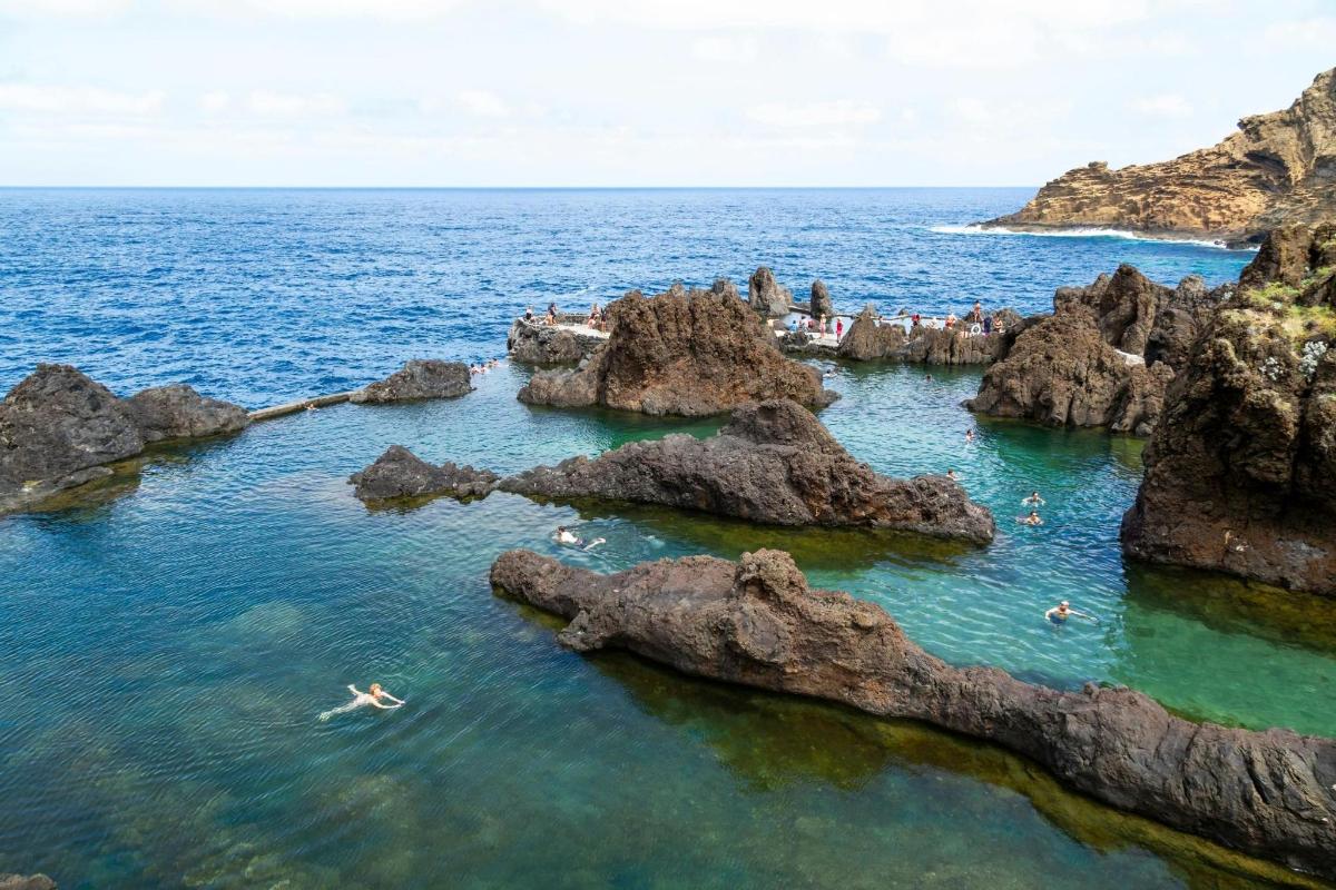 un grup de oameni care înoată în ocean lângă stânci