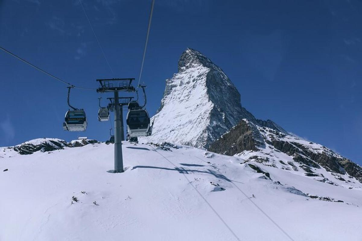 a ski lift in front of a snow covered mountain