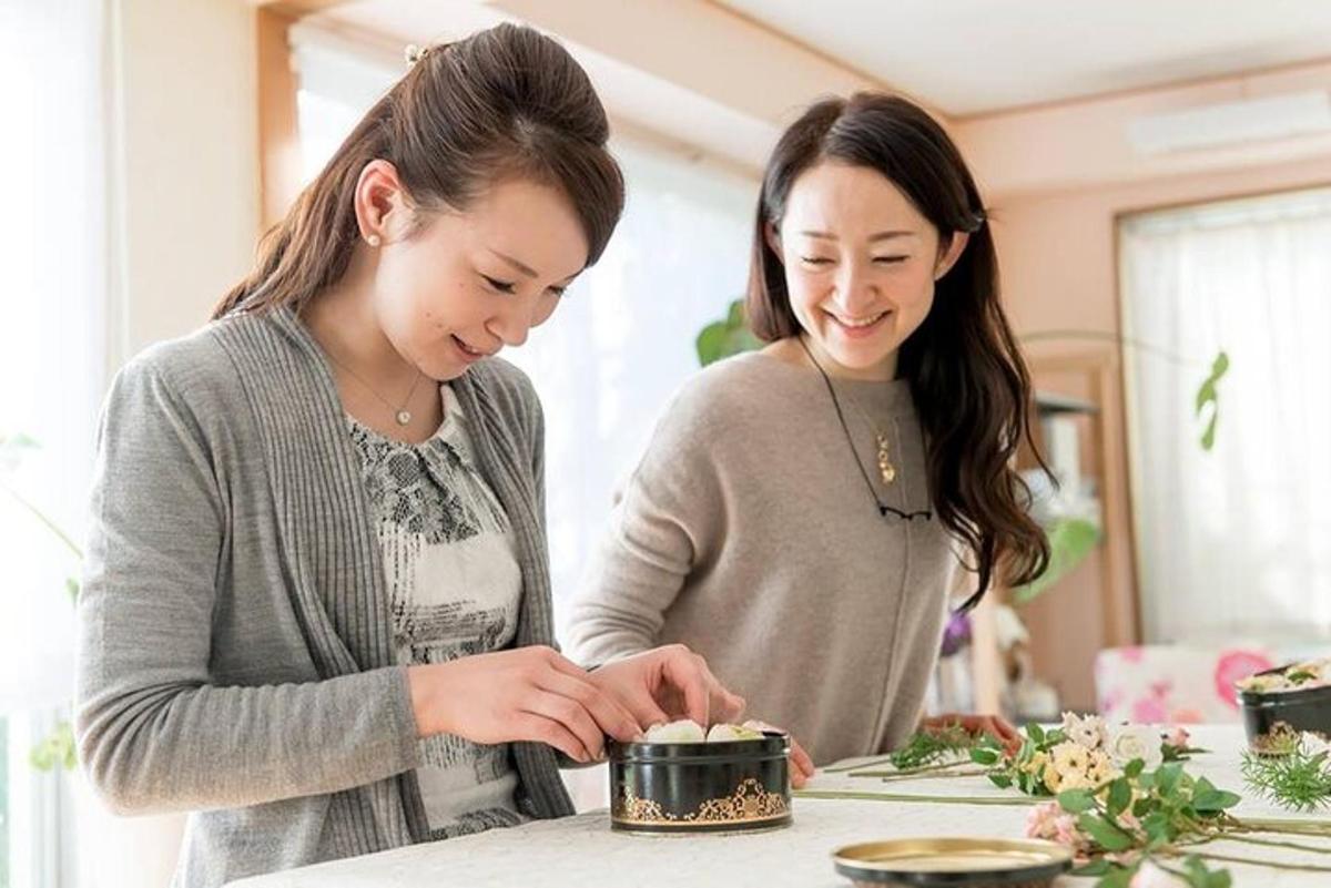 dua wanita berdiri di dapur menyediakan makanan