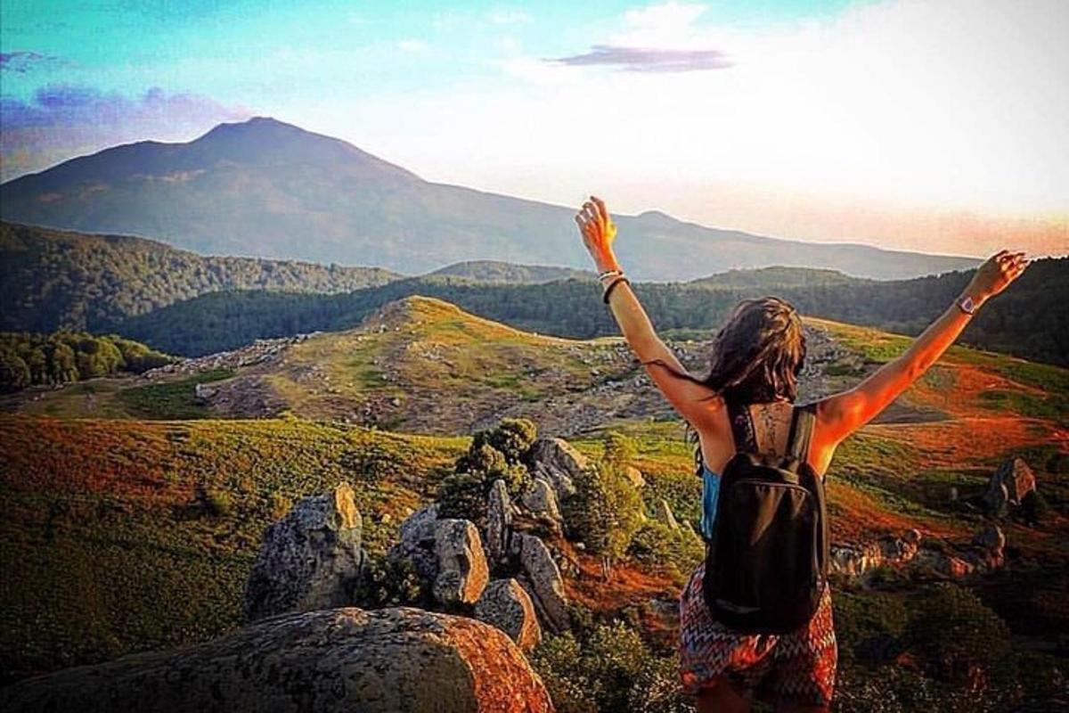 una donna in piedi sulla cima di una montagna con le braccia alzate