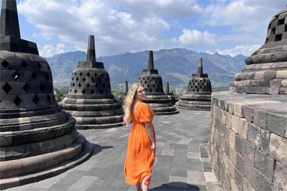 uma mulher com um vestido laranja em pé em frente a um templo