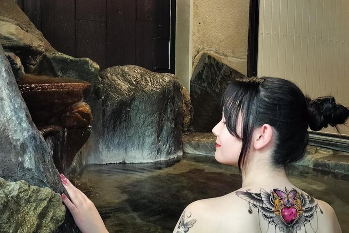 tatuoitu nainen seisoo vesiputouksen vieressä