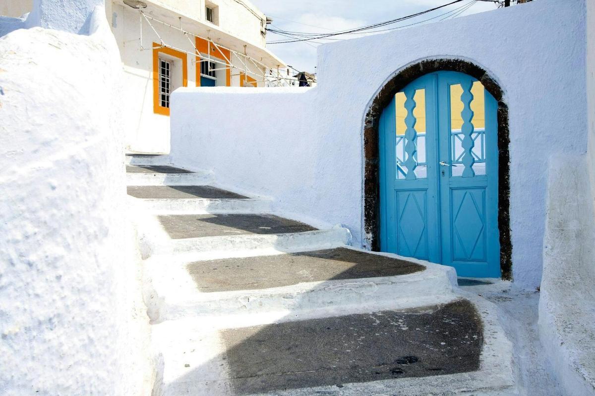 Una puerta azul en un edificio blanco con escaleras.