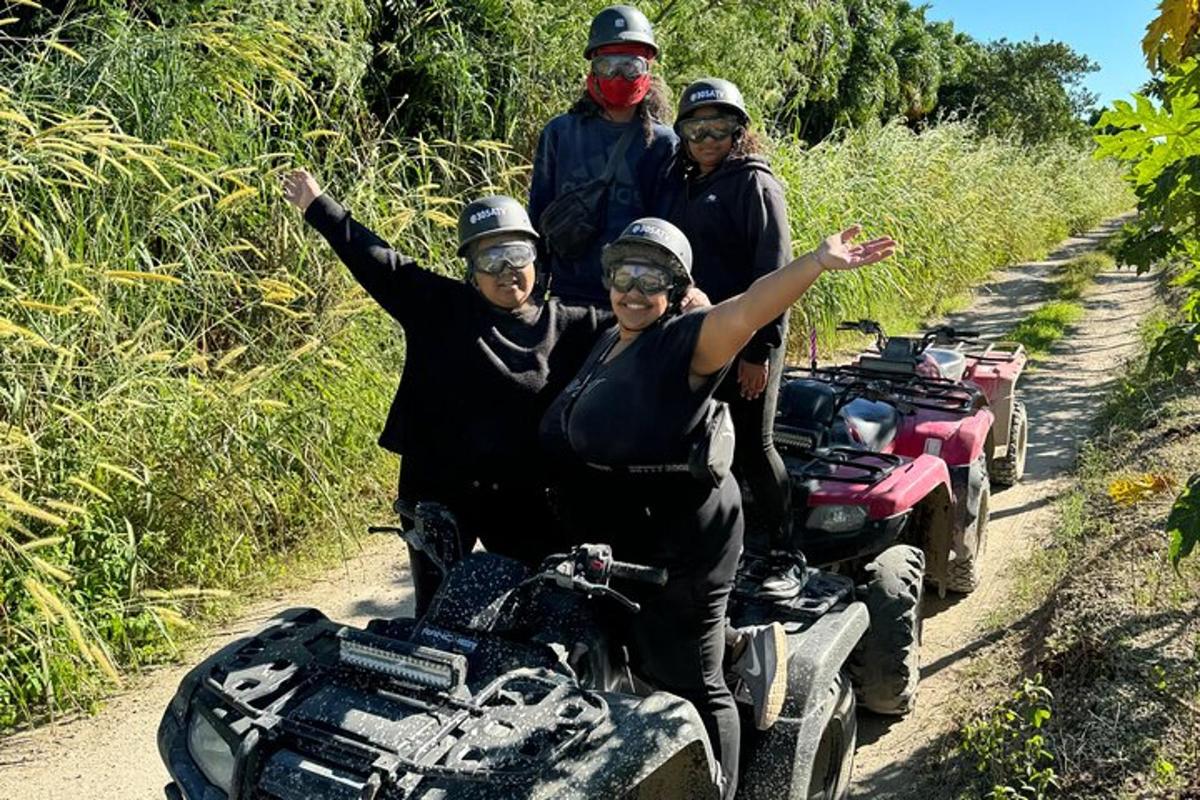 a group of people riding on a quad bike on a dirt road