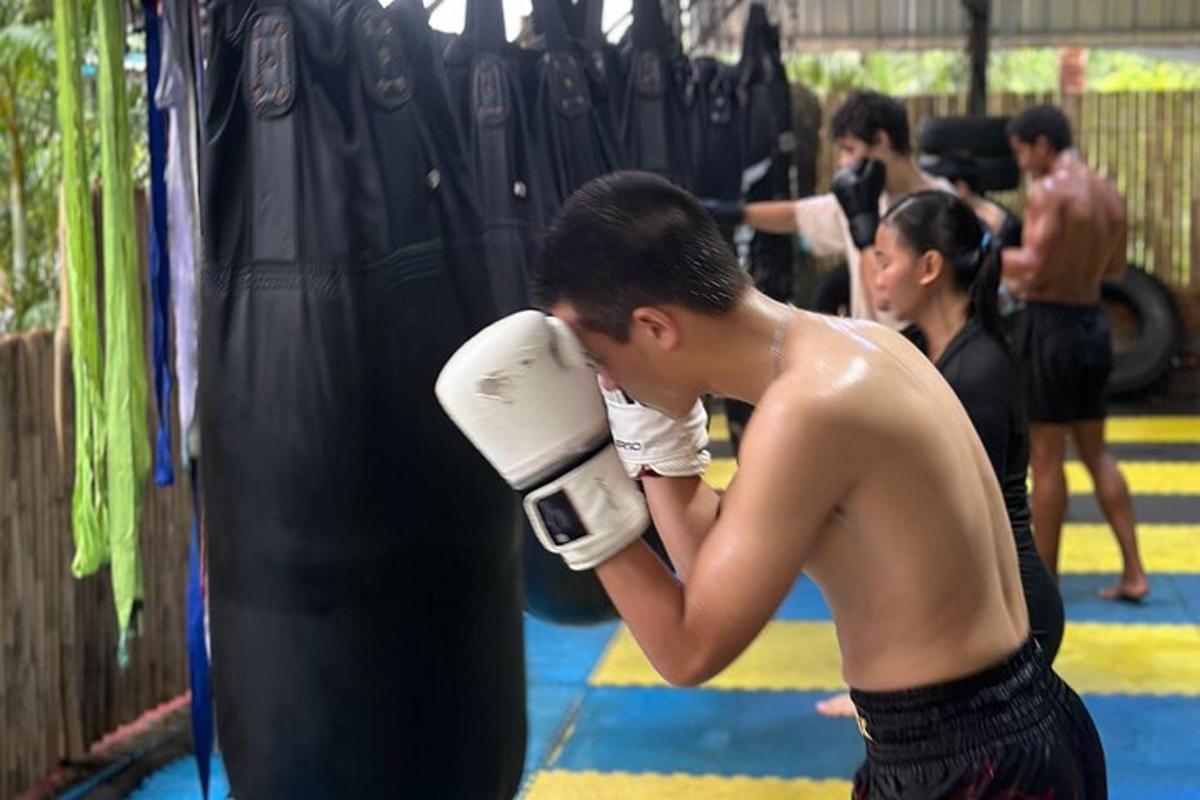 拳击馆里，一名赤裸上身的男子站在沙袋旁边