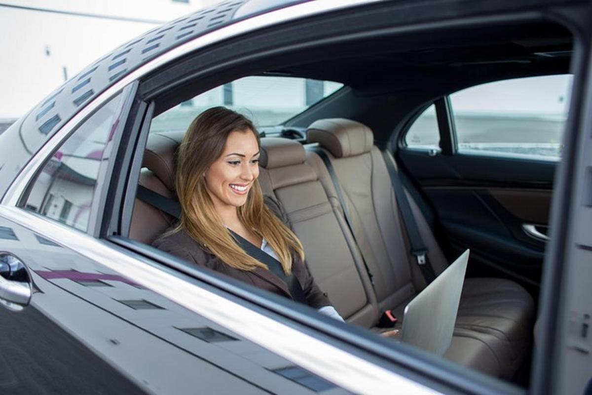 a woman sitting in the back seat of a car with a laptop