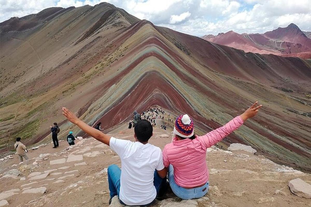 two people sitting on top of a mountain with their arms up