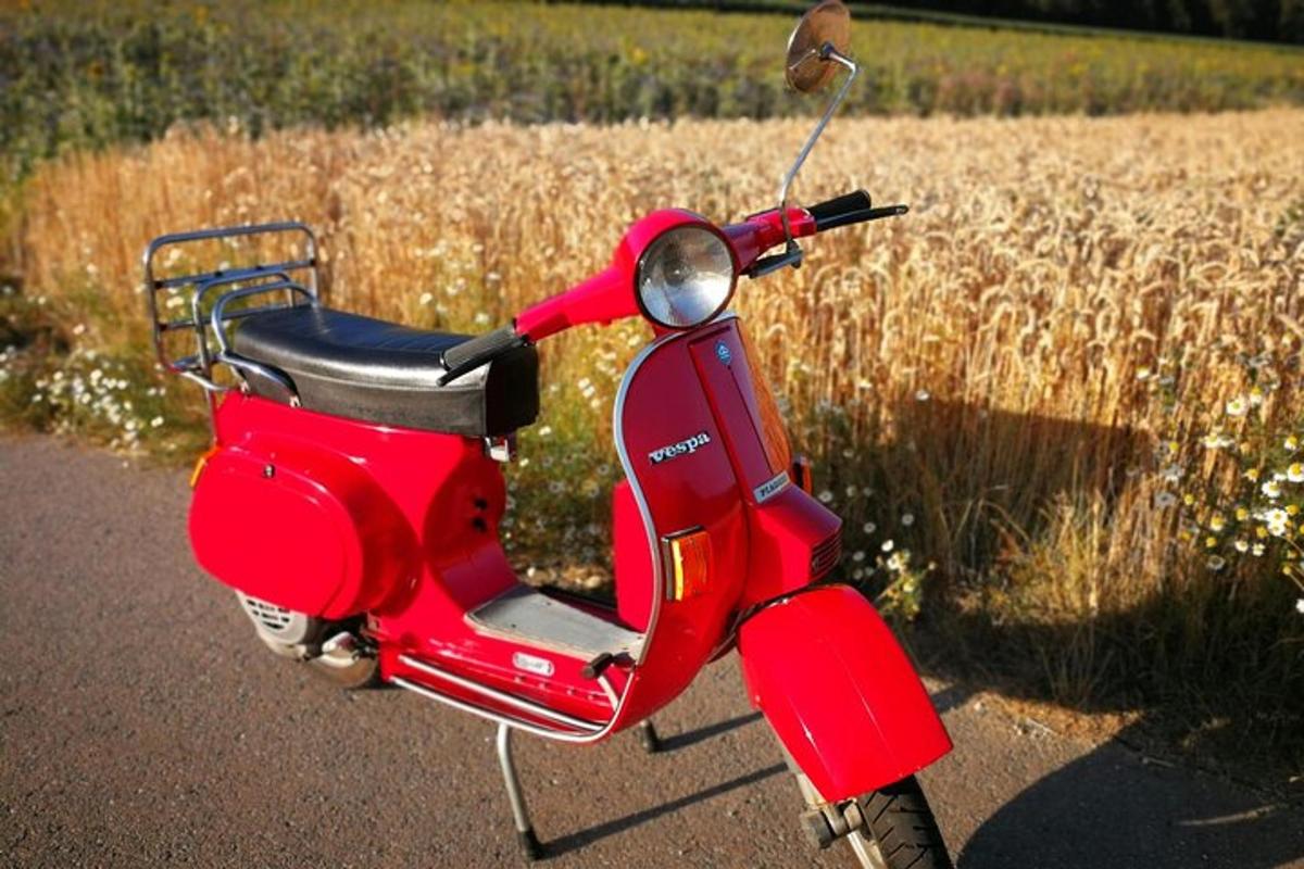 uno scooter rosso parcheggiato su una strada accanto a un campo