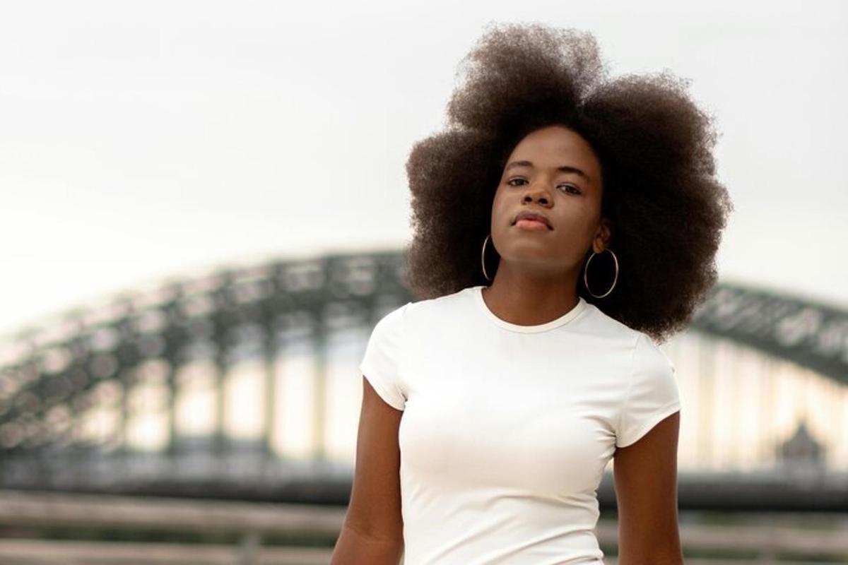 a woman with an afro standing in front of a bridge