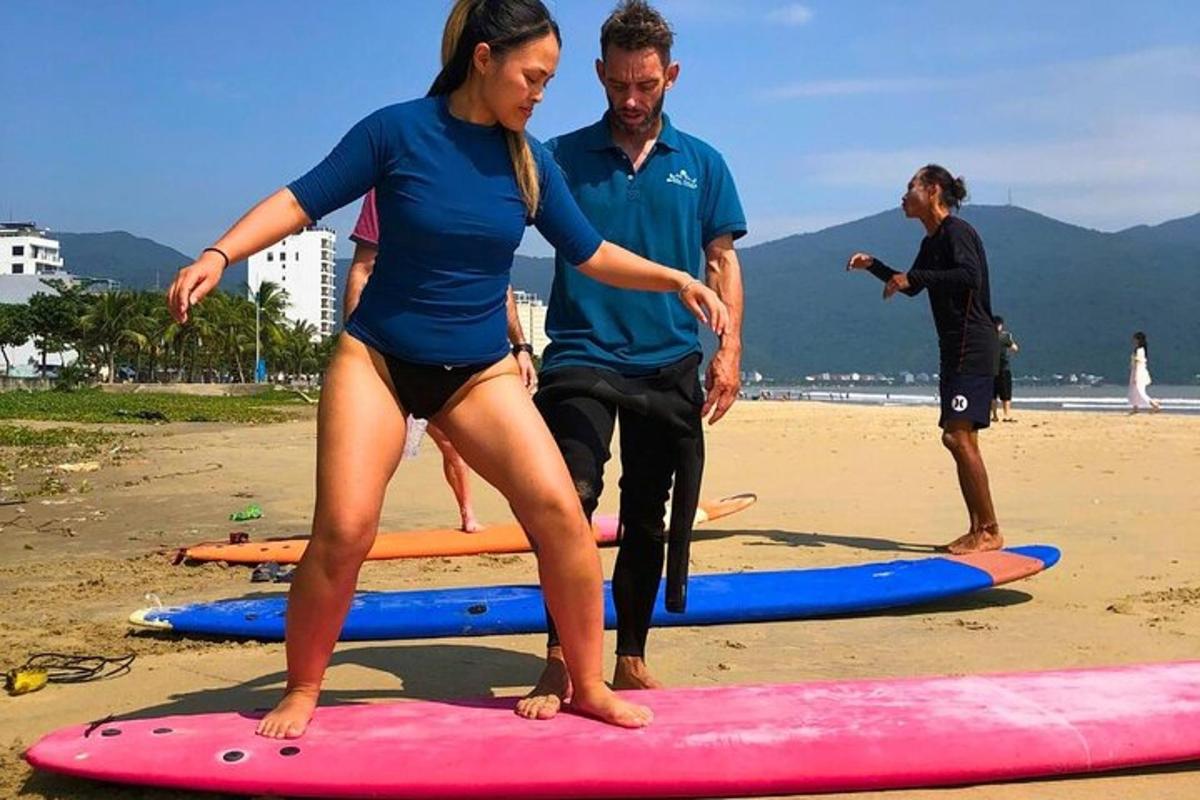 a woman standing on a surfboard on the beach