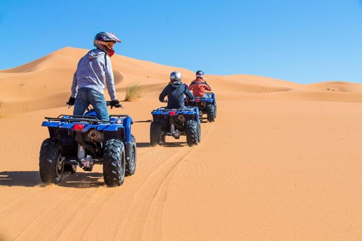 tre persone in sella a quad nel deserto