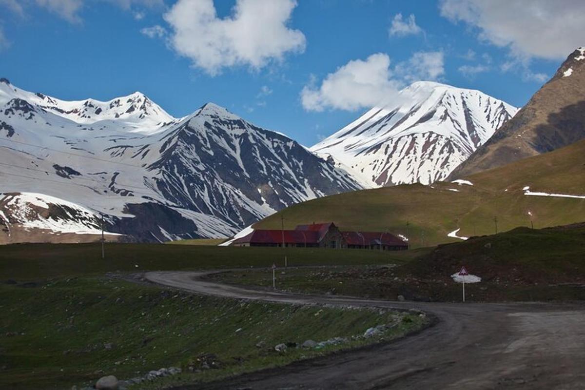 una catena montuosa coperta di neve con una casa su una strada