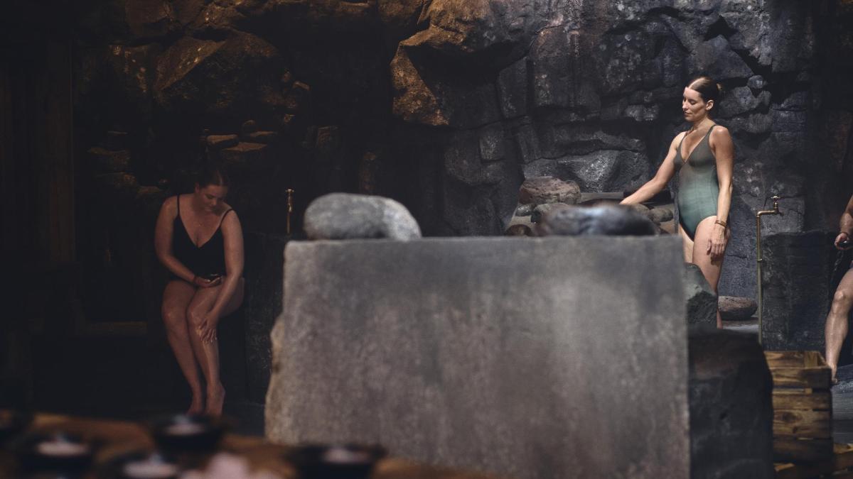 two women are standing in a stone bathtub