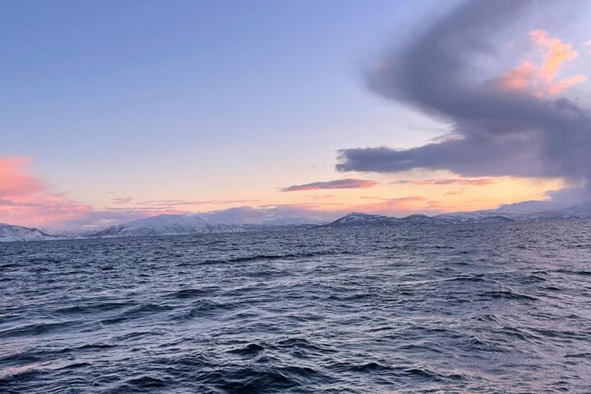 a sunset over the ocean with mountains in the distance