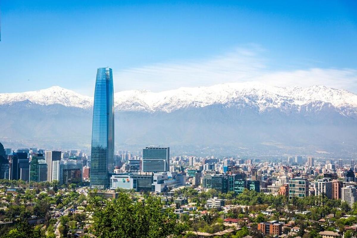 a city with a tall skyscraper in front of snowy mountains