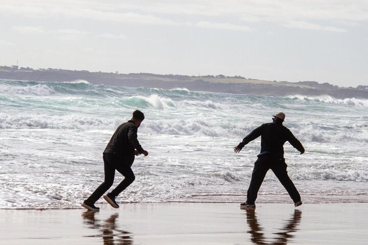 two men walking on the beach near the ocean
