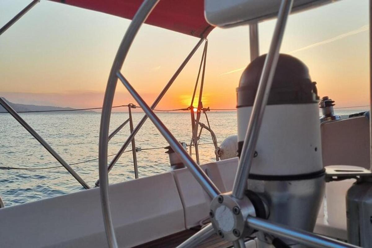 um homem sentado em um barco no oceano ao pôr do sol