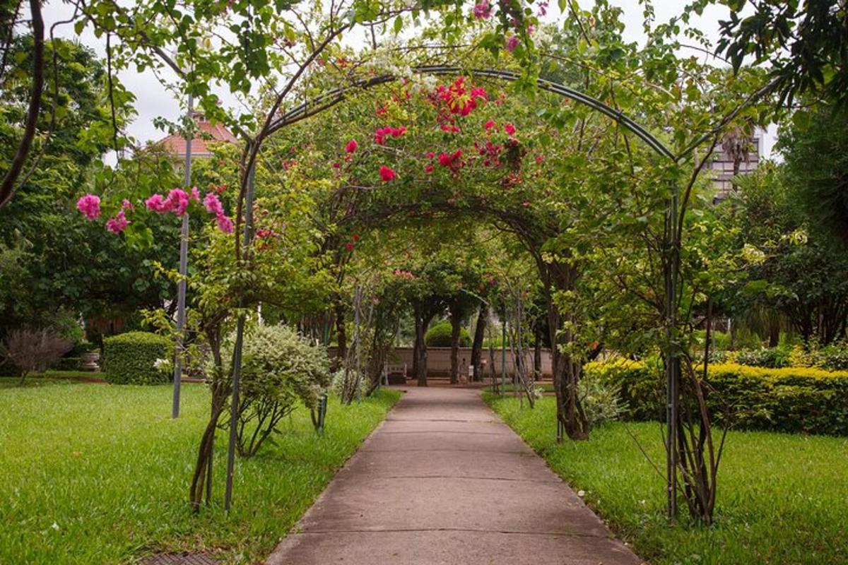 a garden with an arch with pink flowers