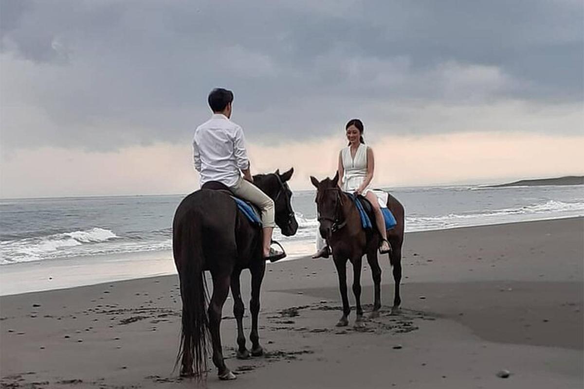 một người đàn ông và một người phụ nữ cưỡi ngựa trên bãi biển