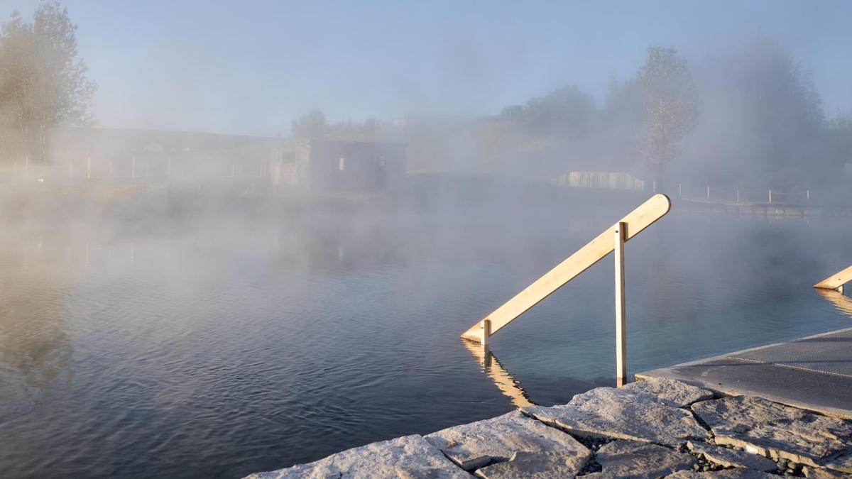 a misty lake with a white railing in the water