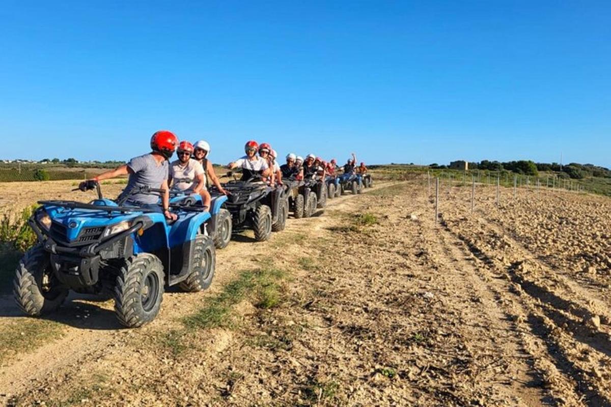 grupė žmonių, važiuojančių keturračiais purvinu keliu