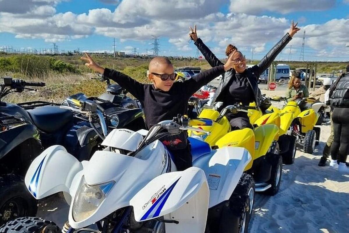 du žmonės sėdi ant motociklų, pakėlę rankas į viršų