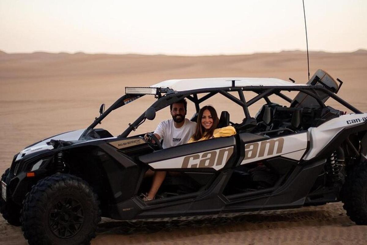 Un hombre y una mujer sentados en un vehículo todo terreno en el desierto.