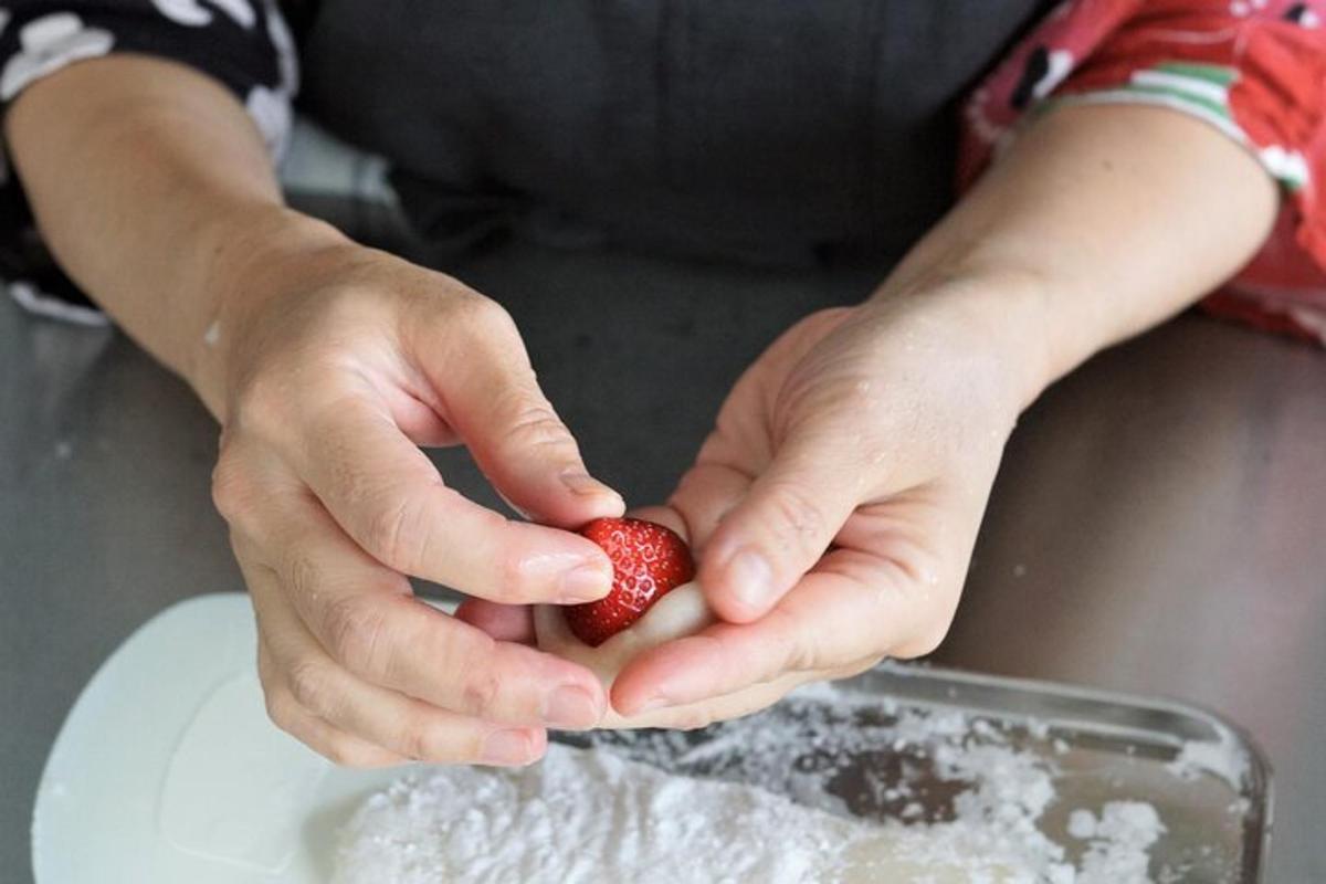 una persona che tiene una fragola in una ciotola di zucchero