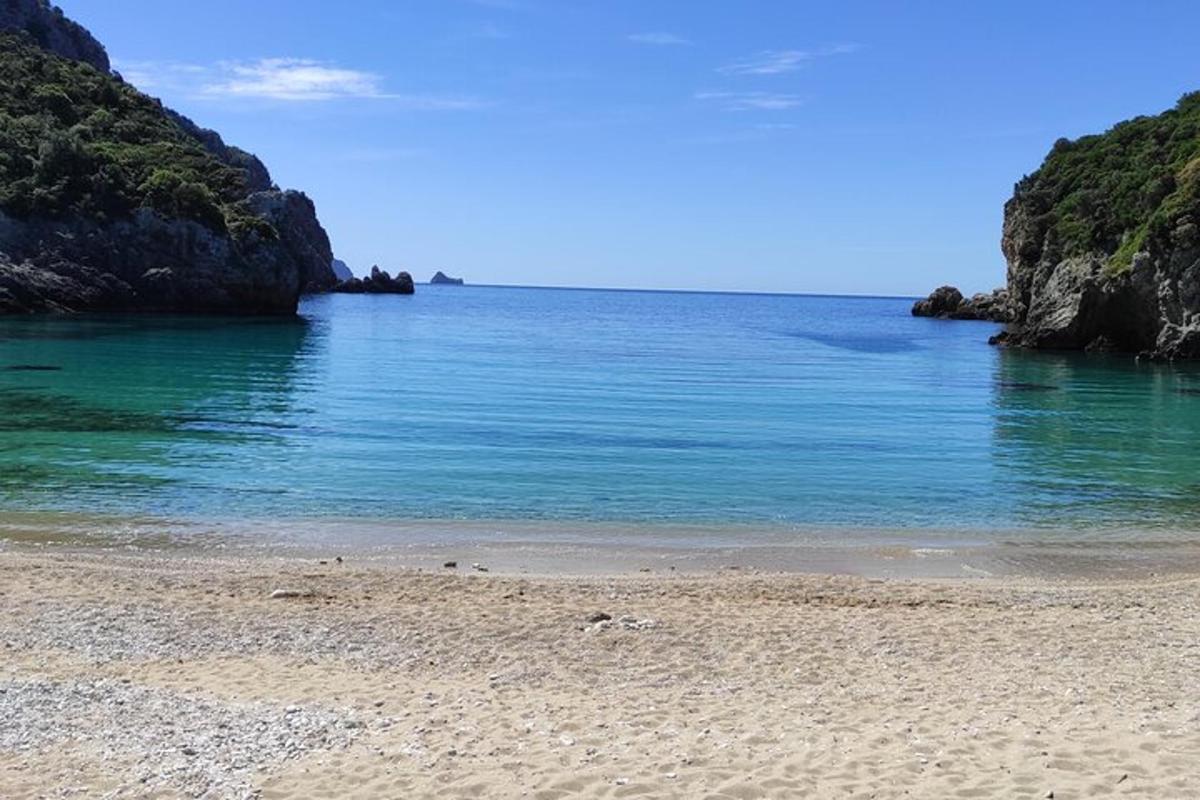 Una playa con agua azul y rocas en el océano.