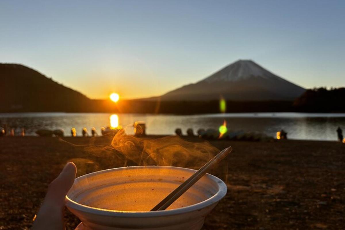 a bowl of soup with a chopstick in front of a lake