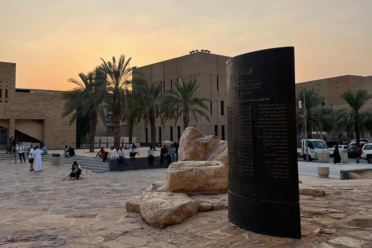 a monument in front of a building with people walking around